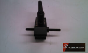 Black mechanical component with a protruding vertical shaft on a white surface.