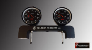 Two black automotive gauges mounted on a metal bracket labeled Del-Tron Products.