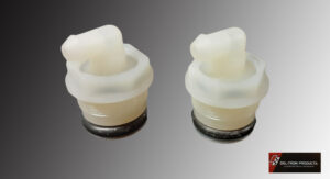 Two white plastic bottle stoppers with black bases on a gray surface.