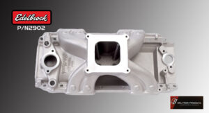 Silver engine intake manifold with rectangular carburetor opening.