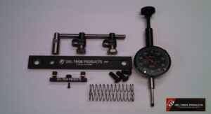 Various mechanical parts and a dial gauge on a white surface.