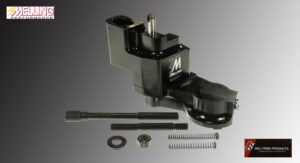 Black mechanical device with spring and small parts on gray background.