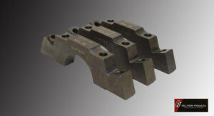 Three aged metal parts with bolts on a gray background.