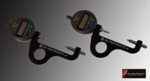 Two precision measuring tools with digital displays on a dark surface.