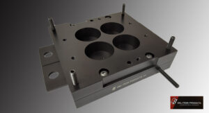 Close-up of a black metal component with four circular recesses and mounting studs.