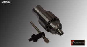 Close-up of a metal drill chuck with a key on a gray background.