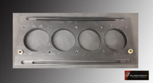 A metal engine part with four circular openings and bolt holes.